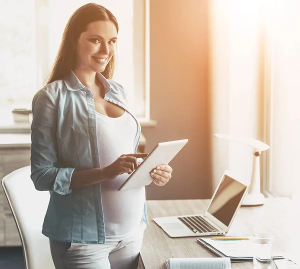 Fiatal boldog terhes nő segítségével a digitális tábla. — Stock Fotó