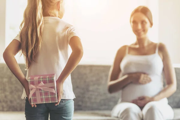 Liten flicka håller gåva bakom rygg för mamma. — Stockfoto