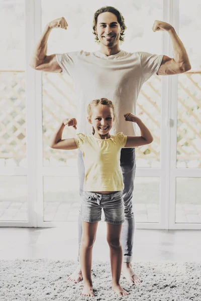 Красивый мужчина и симпатичная маленькая девочка демонстрируют мускулы . — стоковое фото
