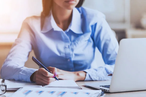 Junge Frau schreibt Notizen in Notizbuch im Büro. — Stockfoto