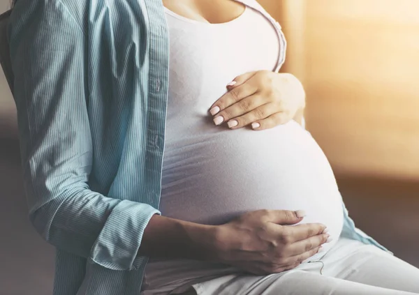 De cerca. Embarazada mujer sosteniendo manos en el vientre . —  Fotos de Stock