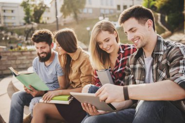 Park ve okumak kitap içinde oturan genç insanlar.