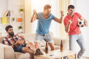Gençler evde futbol izlerken bira ile.