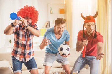 Üç arkadaş evde futbol takımı için köklenme.