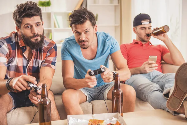 Trois jeunes hommes heureux jouant à des jeux vidéo à la maison . — Photo