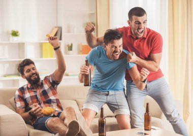 Gençler evde futbol izlerken bira ile.
