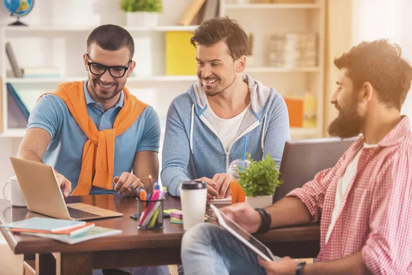 Hombres sonrientes trabajando con computadoras portátiles y tabletas . — Foto de Stock