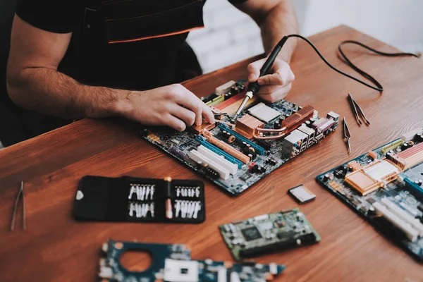 Yakın çekim. Genç tamiri anakart Pc. tamircisi adam. Araçları ile çalışan. Bilgisayar donanım. Büyüteç Camı. Havya. Dijital aygıt. Laptop üstünde okul sırası. Elektronik cihazlar kavramı.