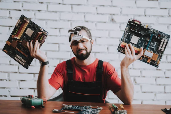 Dükkanda kırık anakartlar genç adam üniformalı. Modern atölye kavramı. Üretim aracı. Modern araçları kavramı. Elektronik cihazlar kavramı. Mobil aygıt donanım. Ahşap Resepsiyon.