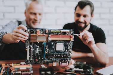 İki adam Pc. onarım donanım ekipmanları tamir dükkanı. Araçları ile çalışan. Bilgisayar donanım. Genç ve yaşlı işçi. Modern cihazlar. Dijital aygıt. Laptop üstünde okul sırası. Elektronik cihazlar kavramı.