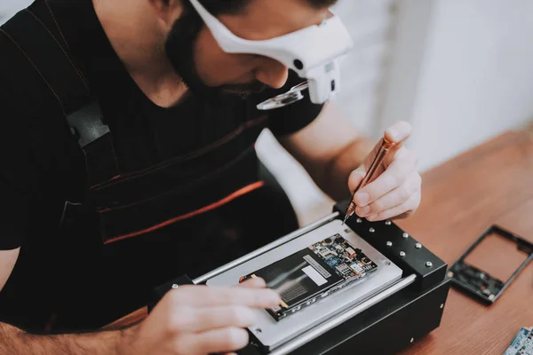 若い男の修理店で修理のハードウェア機器です ツールの労働者 コンピューターのハードウェア 電子機器のコンセプトです ひげを生やした男現代装置 デジタル デバイス 眼鏡の男 — ストック写真