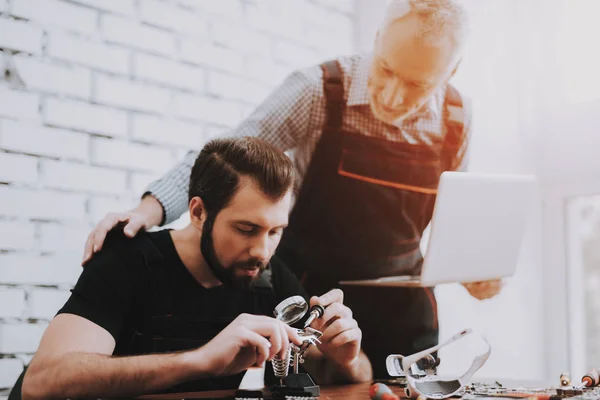 Two Men Repairing Hardware Equipment in Workshop. Repair Shop. Worker with Tools. Computer Hardware. Young and Old Workers. Modern Devices. Digital Device. Laptop on Desk. Electronic Devices Concept.