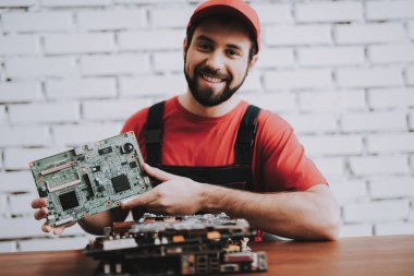 Atölye kırık anakartlar genç adam kırmızı şapkalı. Modern atölye kavramı. Üretim aracı. Modern araçları kavramı. Elektronik cihazlar kavramı. Mobil aygıt donanım. Ahşap Resepsiyon.