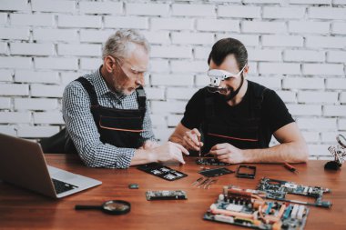 Hareket eden telefon içinde Modern Atölye tamir iki adam. Dükkanı onarın. Genç ve yaşlı işçi. Dijital aygıt. Gözlüklü adam. Elektronik cihazlar kavramı. Mobil aygıt donanım. Araçları arkadaşlarınızla.