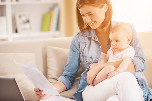 Jeune femme avec bébé travaillant à la maison avec ordinateur portable . — Photo