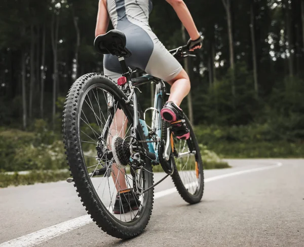 Jovem mulher andando de bicicleta na montanha perto da floresta — Fotografia de Stock