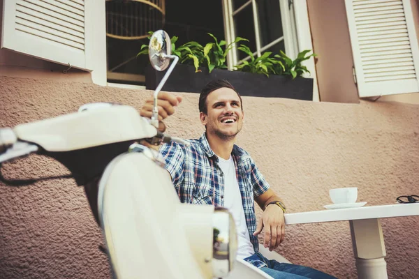 Fröhlicher Mann sitzt am Tisch und hält Roller. — Stockfoto