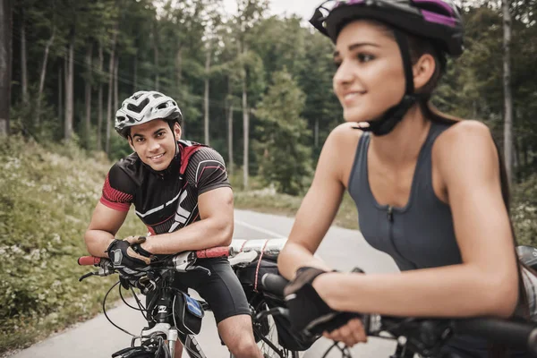 Jovens casais andando de bicicleta na estrada da floresta . — Fotografia de Stock