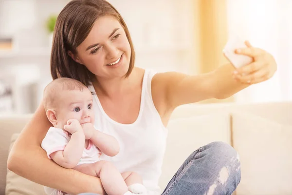 Smartphone kullanarak ve bebek tutan mutlu anne. — Stok fotoğraf