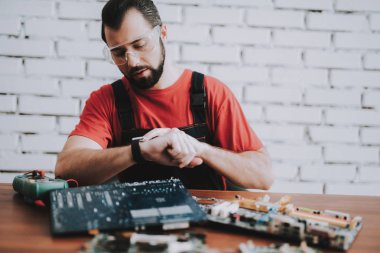 Dükkanda kırık anakartlar genç adam üniformalı. Modern atölye kavramı. Üretim aracı. Modern araçları kavramı. Elektronik cihazlar kavramı. Mobil aygıt donanım. Ahşap Resepsiyon.