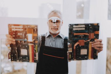 Eski işçi anakartlar elinde duran. Alt donanım ile. Modern atölye kavramı. Adam Modern aygıtları duran. Dijital aygıt. Elektronik cihazlar kavramı. Gözlüklü adam.