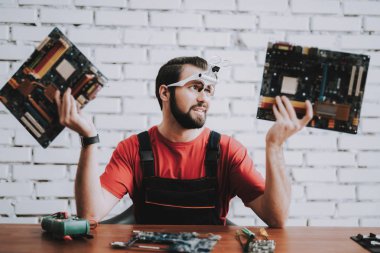 Dükkanda kırık anakartlar genç adam üniformalı. Modern atölye kavramı. Üretim aracı. Modern araçları kavramı. Elektronik cihazlar kavramı. Mobil aygıt donanım. Ahşap Resepsiyon.