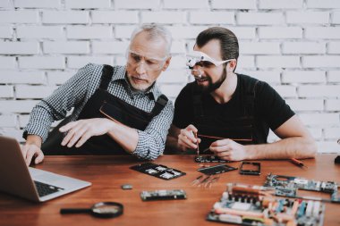 Hareket eden telefon içinde Modern Atölye tamir iki adam. Dükkanı onarın. Genç ve yaşlı işçi. Dijital aygıt. Gözlüklü adam. Elektronik cihazlar kavramı. Mobil aygıt donanım. Araçları arkadaşlarınızla.