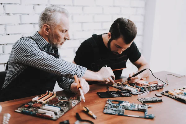 二人の男が 修理からハードウェア機器の修理店します ツールの労働者 コンピューターのハードウェア 古い労働者 はんだごて デジタル デバイス 机の上のノート パソコン — ストック写真