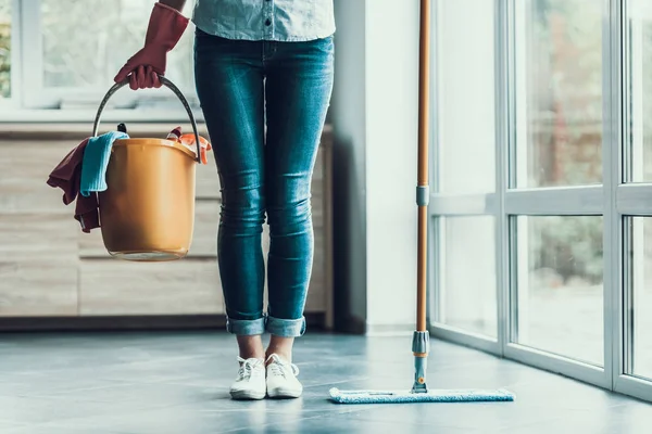 Mujer joven sostiene cubo con equipo de limpieza — Foto de Stock