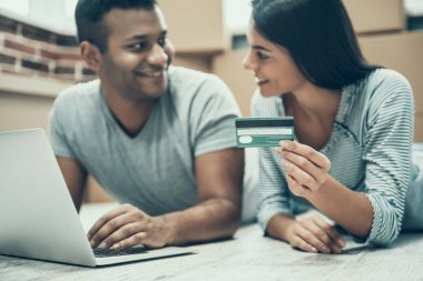 Kaç alışveriş Online üstünde Laptop gülümseyen genç. Genç güzel yakışıklı genç adam Online ödeme sırasında Crtedit kart yığını zemin üzerine karton kutu ile Laptop istimal tutan kadın