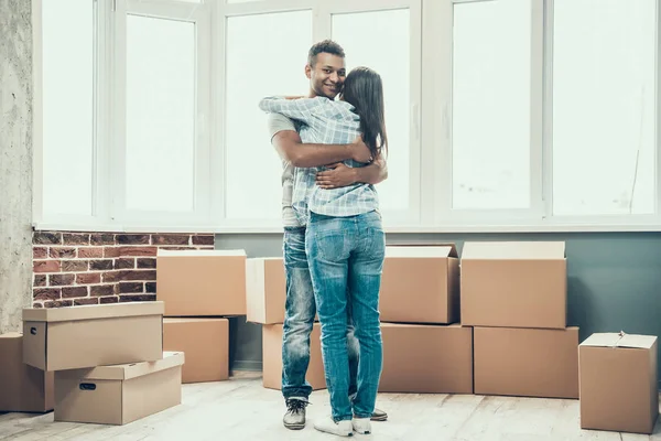 若いカップルの笑顔では 新しい家に移動をお楽しみください 若い美しいカップルを抱いて 空のアパートの背景に段ボール箱のスタック 移転と家の概念を移動します — ストック写真