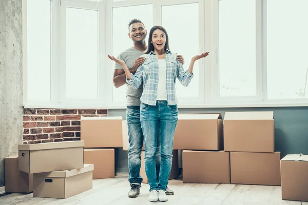 若いカップルの笑顔では 新しい家に移動をお楽しみください 若い美しいカップルを抱いて 空のアパートの背景に段ボール箱のスタック 移転と家の概念を移動します — ストック写真