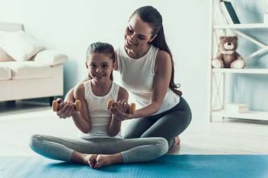 Genç kadın ve küçük kız Fitness Egzersiz yapmak. Güzel genç anne sevimli küçük kızını öğretir nasıl egzersiz Dumbbells ile yapılır. Anne ve kızı birlikte evde. Sağlıklı yaşam tarzı