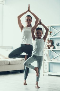 Genç kadın ve küçük kız poz Yoga yapıyor. Güzel genç anne ve egzersiz sırasında sevimli küçük kız. Anne ve kızı evde Yoga birlikte pratik. Sağlıklı yaşam tarzı