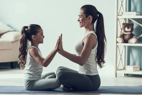 Genç kadın ve küçük kızı egzersiz sonrası dinlenme. Güzel genç anne ve Yoga Mat sevimli küçük kızı oturuyor. Anne ve kızı birlikte evde. Sağlıklı yaşam tarzı