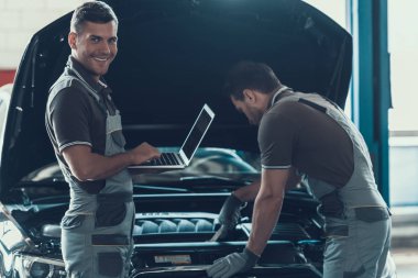 Otomatik olarak çalışan iki araba mekanik onarım servisi. Profesyonel beyaz yakışıklı mutlu çalışanlar üniforma ve otomobil dizüstü kullanarak açılan başlık ile onarmak eldiven. Onarım hizmet anlayışı.