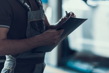 Otomatik mekanik yapımı araba muayenesi Close-up. Tek tip yazı ve Pano servis siparişi izole mevsimlik artalanları üzerinde tutan adam. Onarım Servisi. Adam araba tamir kavramı