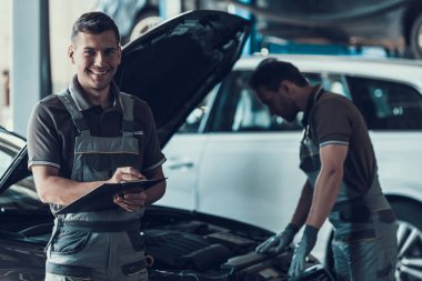 Garajda iki tane yakışıklı tamirci var. Teftişten sonra araba kontrol formlarını doldururken 