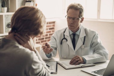 Ciddi Doktor Tanı Kadın Hasta Diyor. Doktor Ciddi İfade ile Hasta bakıyor. Kabinede Masada Oturan Kendine Güvenen Sağlık Çalışanı. Doktor Randevusu. Tıbbi Sorun Kavramı