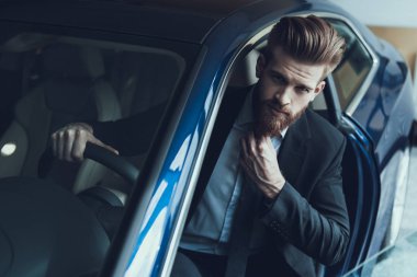 Araba Sakalı ve Dümeni 'ndeki yakışıklı Buisinessman. Şık Sakallı, Kafkasyalı Mavi Giysili Siyah Takımlı, Ciddi İfadeyle Kameraya Bakan Kişinin Portresi