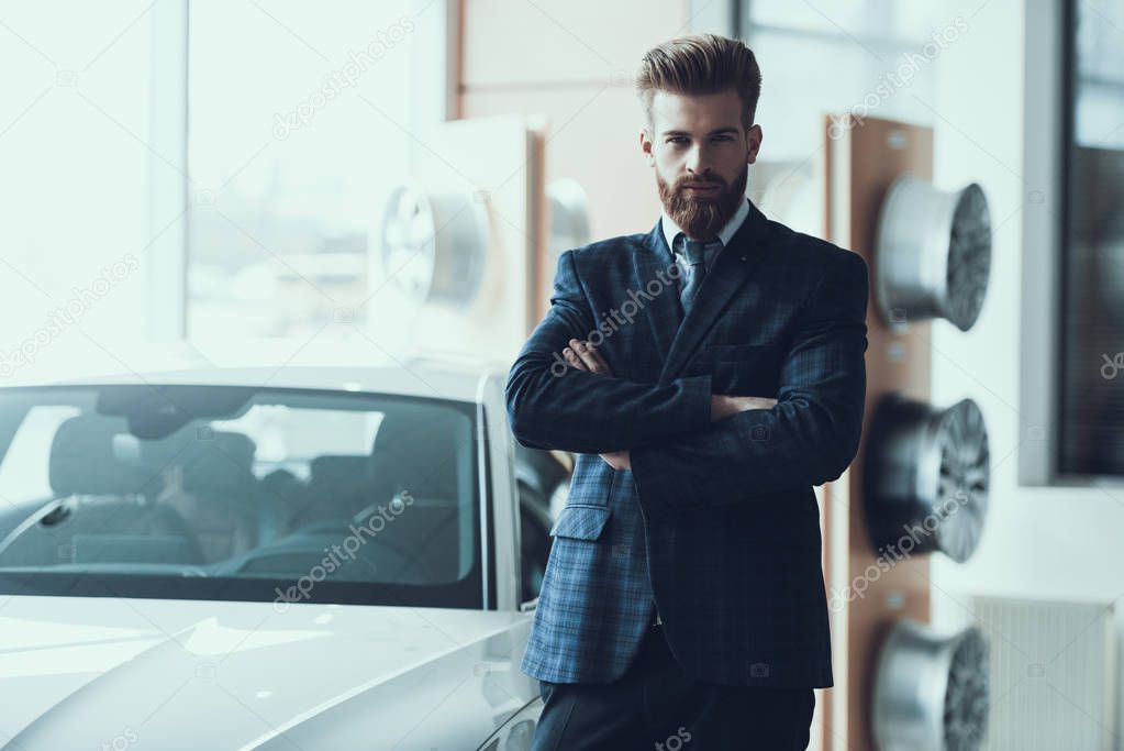 Handsome Bearded Businessman Standed near Car. Portrait of Stylish Confident Caucasian Person Posing with Crossed Arms Wearing Dark Checkered Suit Looking at Camera with Serious Expression