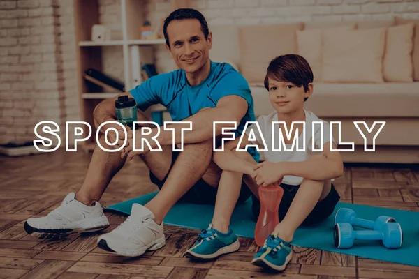 Baba ve oğul spor salonu halı üzerinde dinlenme. Sağlıklı bir yaşam tarzı. Aktif tatil. Spor kıyafetler. Evde çalışma dışarı. Su şişesi. Vücut egzersizleri. Aile eğitim gün kavramı.