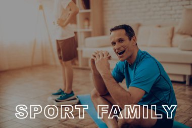 Baba spor salonu Carpert bir Burger yemek oturuyor. Oğlunun ağırlığında arka plan. Sağlıklı bir yaşam tarzı. Etkin aile. Yazılmamış beslenme. Ağırlık ölçümü. Ölçekte bak. Spor kıyafetler. Silah Akimbo.