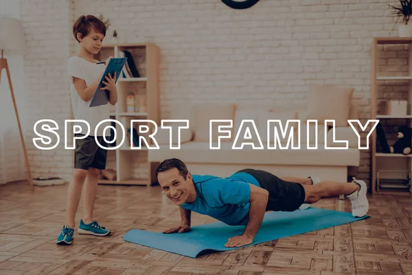 Baba gülümseyerek itme yapıyor Ups. Spor aile. Sağlıklı bir yaşam tarzı. Aktif tatil. Giysi uygular. İyiye gidiyor. Evde çalışma dışarı. Spor salonu halı. Uygulama yineleyin. Tablet sonuçlarına.