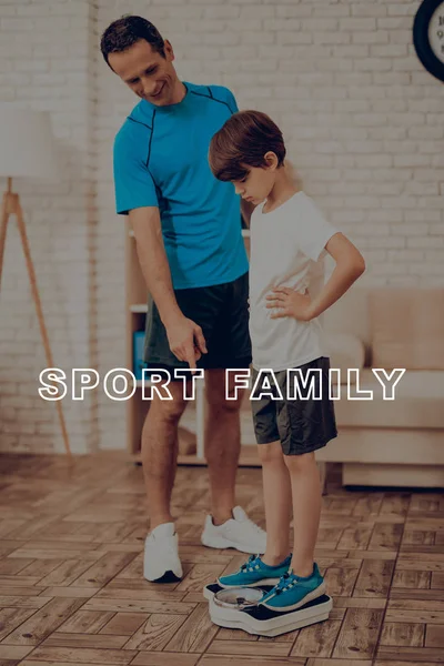 Father And A Son Are Weighing. Sport Concept. Healthy Lifestyle. Active Family. Happy Childhood. Weight Measurement. Look On Scale. Gym Clothes. Arms Akimbo. Exercising At Home. Holiday Leisure.
