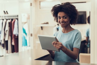 Mağazada Tablet Kullanan Kadın Çalışan. Mall içinde Butik İş Tablet kullanarak Afro saç modeli ile Güzel gülümseyen Afrikalı Kadın. Giyim Mağazasında Çalışan Çekici Genç Kız