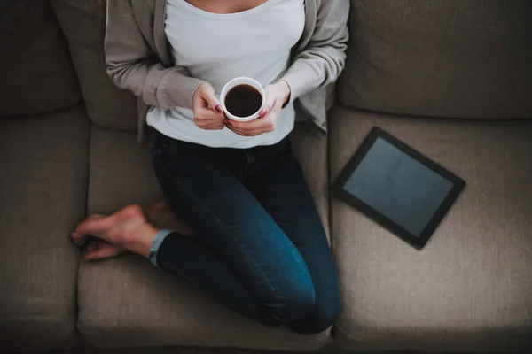 Mulher bonita nova com xícara de café no sofá — Fotografia de Stock