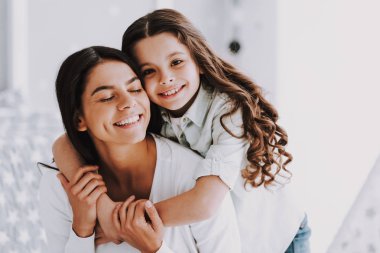 Genç Anne ve sarılma gülümseyen küçük kızı. Mutlu sevimli küçük kız sarılma yetişkin kadının yanına Winwow. Genç kadın ve sevimli kızı birlikte. Aile ve annelik kavramı