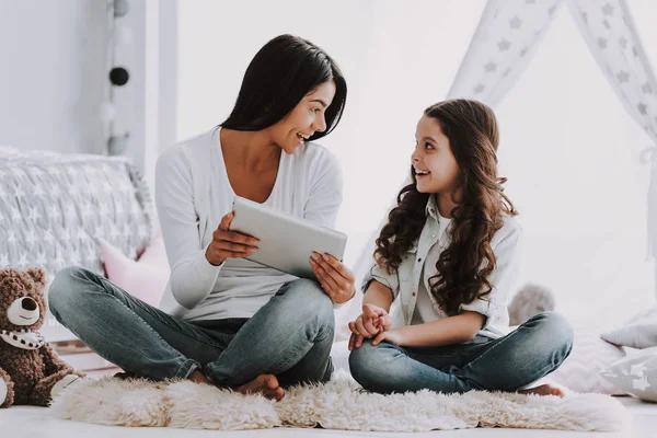年轻的母亲和小女儿用平板电脑 美丽的微笑女人坐在地毯上 在桌面上向可爱的女儿展示一些东西 妈妈在家里给孩子读书 家庭和母性概念 — 图库照片
