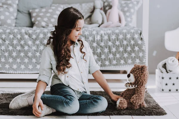 可爱的小女孩和泰迪熊坐在地毯上 笑笑可敬的小女孩坐在床边的饼干上 在家里玩熊玩具 睡房里漂亮的小女孩 童年概念 — 图库照片